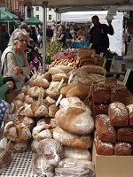 woman purchasing bread that is fresh at a farmers market